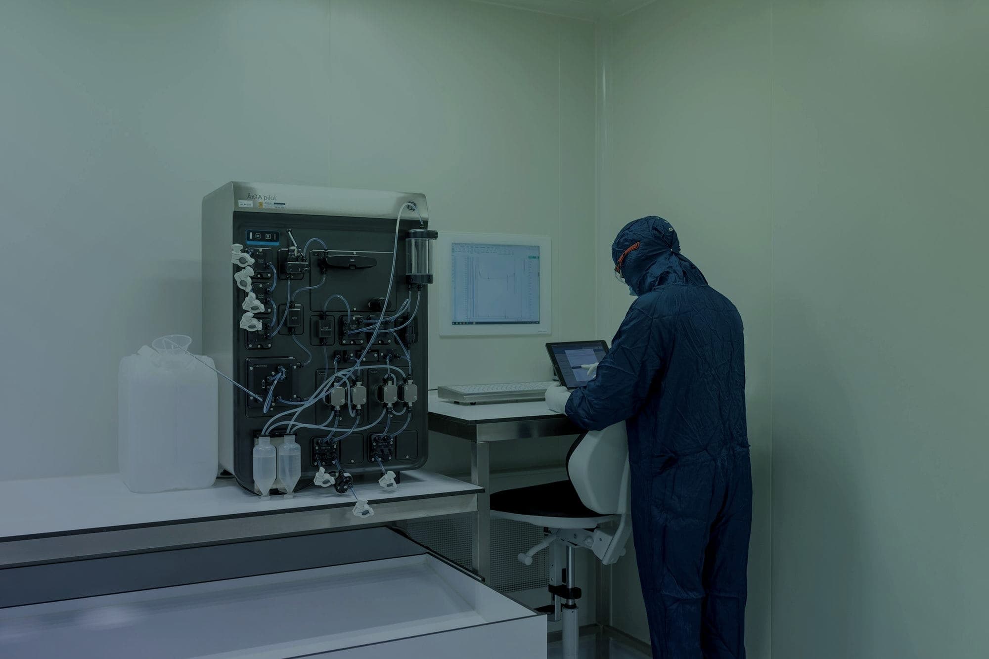 Technician in a clean-room suit operating laboratory automation equipment