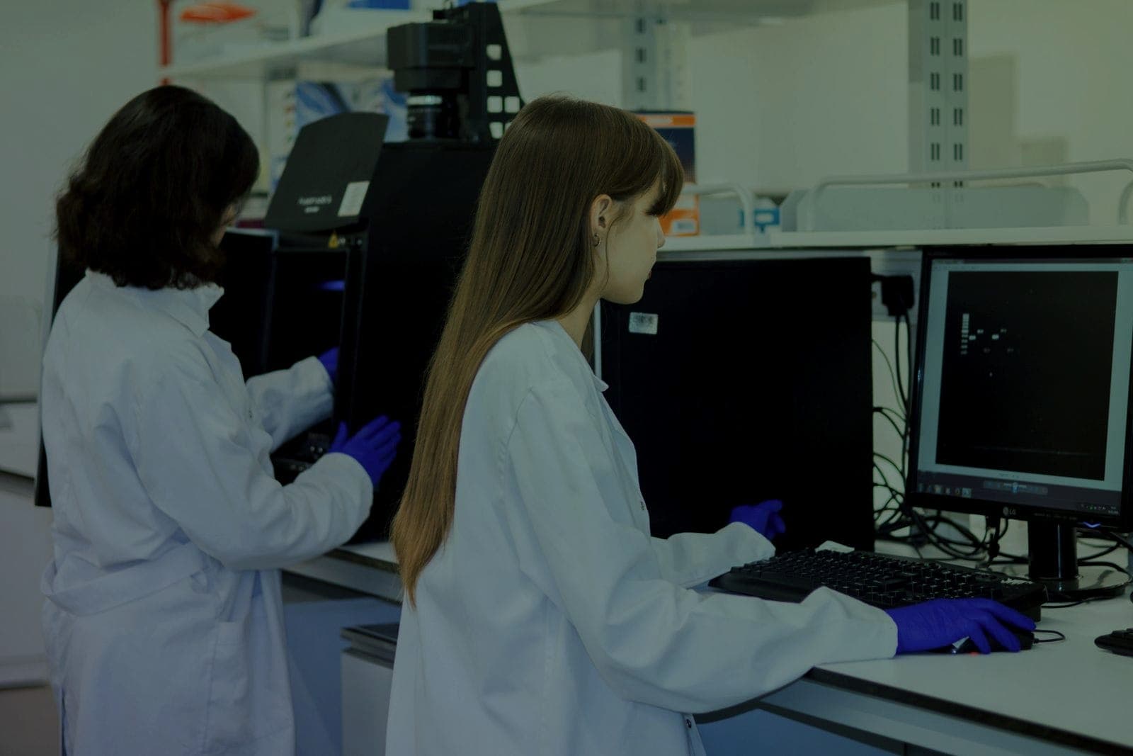 Two scientists in lab coats working at computers in a research laboratory